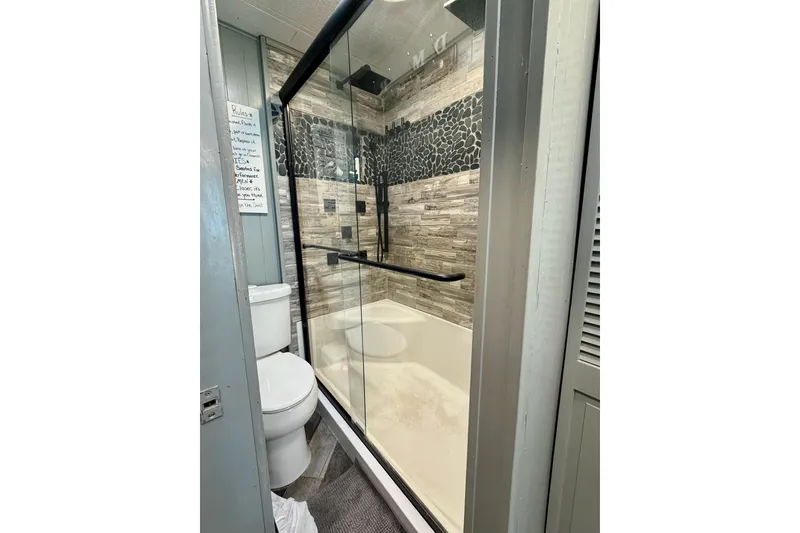 Slide: The Image of Modern bathroom in 1989 Sumerset 14x62 houseboat with glass shower and stone tile accents. - 15