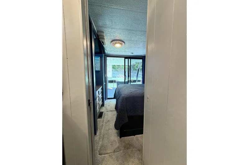 Slide: The Image of Cozy bedroom interior of 1989 Sumerset 14x62 houseboat with natural light and carpeted floor. - 17