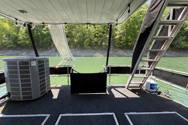 Slide: The Image of 1989 Sumerset 14x62 houseboat deck with lake view, featuring stairs and air conditioning unit. - 28