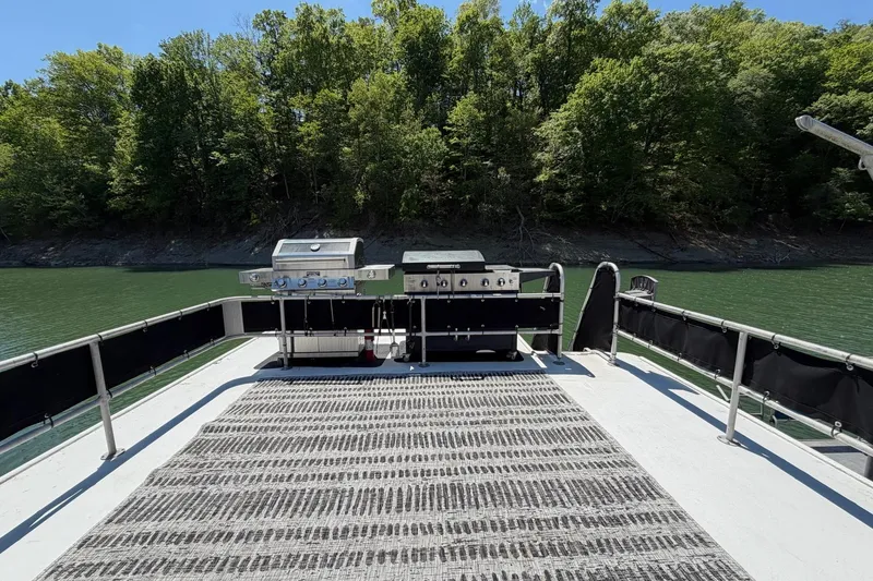 Slide: The Image of 1989 Sumerset 14x62 houseboat deck with grills, surrounded by lush greenery and calm water. - 33