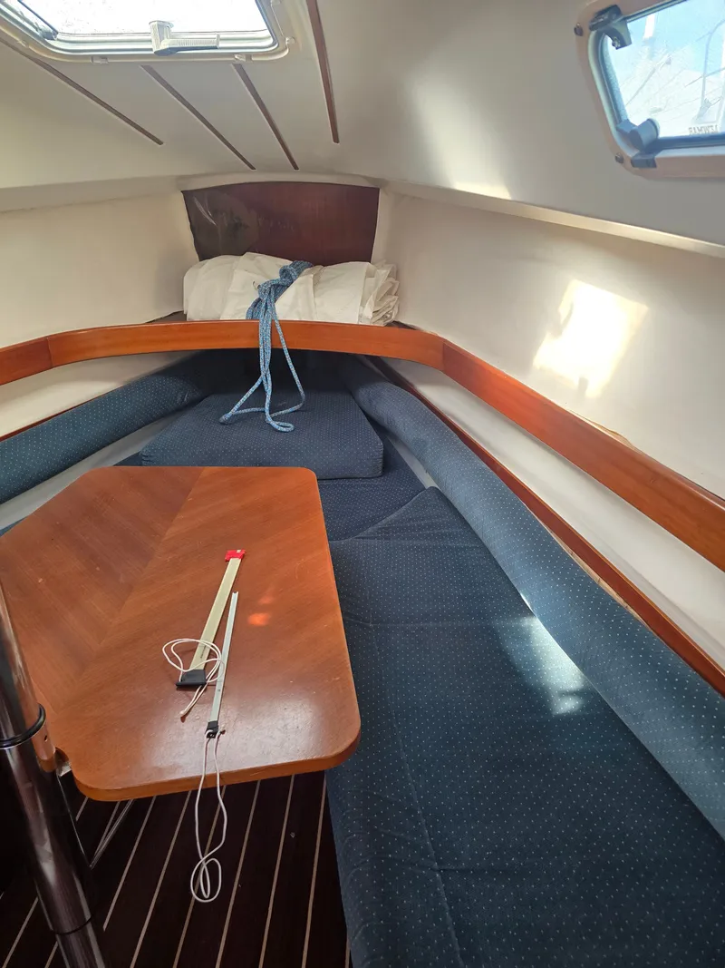 Slide: The Image of Interior of a 1994 Beneteau First 265 yacht with wooden table and blue cushions. - 10