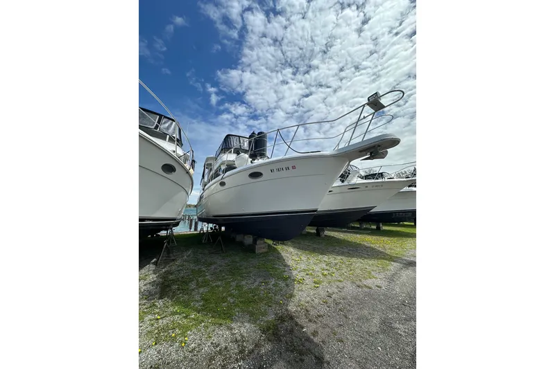 The Image of 1998 Carver 355 Aft Cabin Motor Yacht on display under a partly cloudy sky. - 1