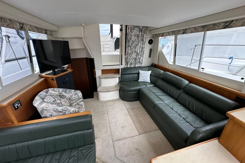 Slide: The Image of 1998 Carver 355 Aft Cabin Motor Yacht interior with green leather seating and TV. - 12