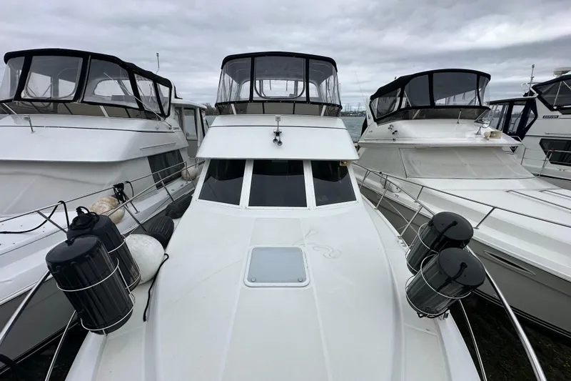 Slide: The Image of 1998 Carver 355 Aft Cabin Motor Yacht docked among similar vessels under cloudy skies. - 15