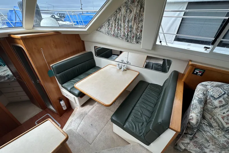 Slide: The Image of 1998 Carver 355 Aft Cabin Motor Yacht interior with dining area and green leather seating. - 8