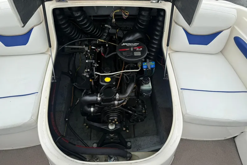 Slide: The Image of 2003 Bayliner 185 boat engine compartment with Mercury 3.0 motor, surrounded by white seating. - 12