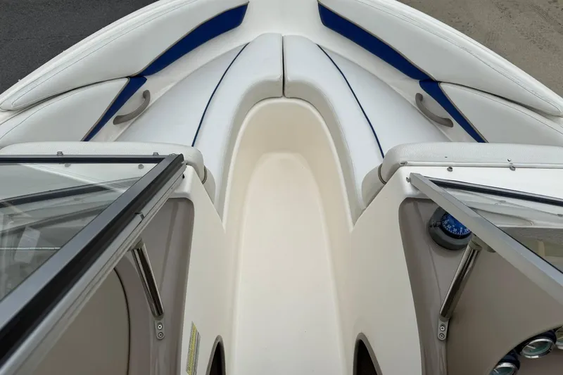 Slide: The Image of 2003 Bayliner 185 boat interior with white and blue seating, open windshield. - 16