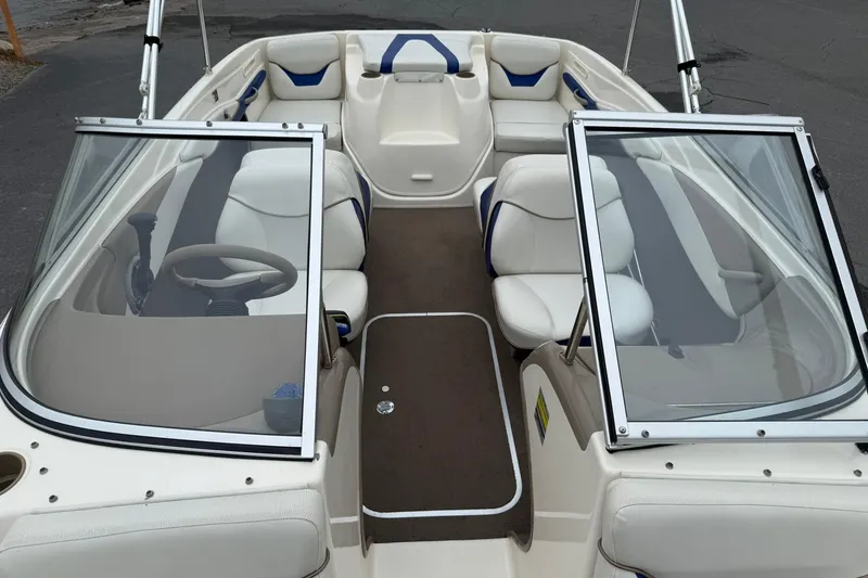 Slide: The Image of 2003 Bayliner 185 boat interior with white and blue seating, open windshield, and steering wheel. - 18