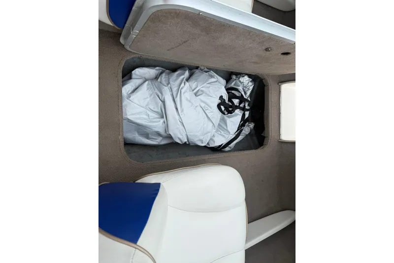 Slide: The Image of Storage compartment in a 2003 Bayliner 185 boat, containing a folded cover. - 19