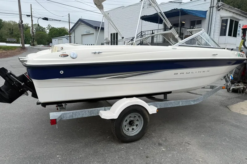 Slide: The Image of 2003 Bayliner 185 boat on trailer, parked outdoors near buildings. - 5