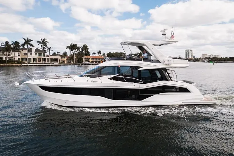 The Image of 2024 Galeon 500 Fly yacht cruising on a scenic waterway with palm trees and luxury homes. - 0
