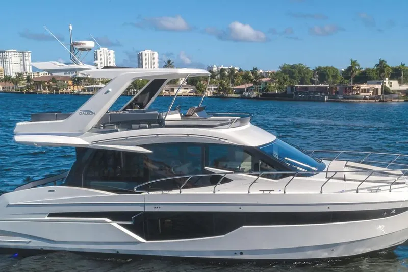 The Image of 2024 Galeon 500 Fly yacht cruising on a sunny day near a coastal city. - 1