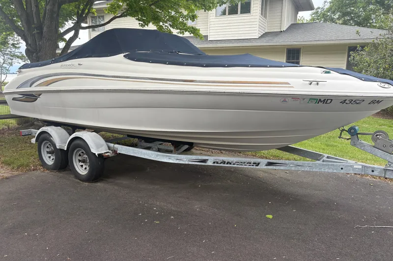 The Image of 2001 Sea Ray 210 Sundeck boat on trailer, parked in driveway near house. - 1