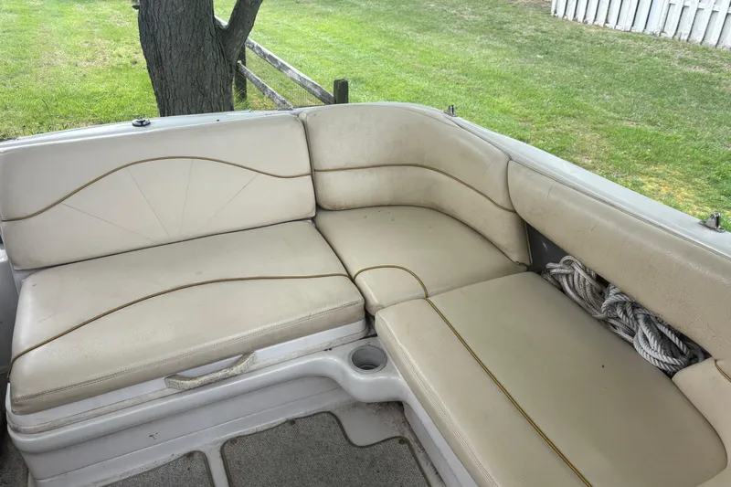 Slide: The Image of 2001 Sea Ray 210 Sundeck interior seating with beige upholstery and rope storage. - 5