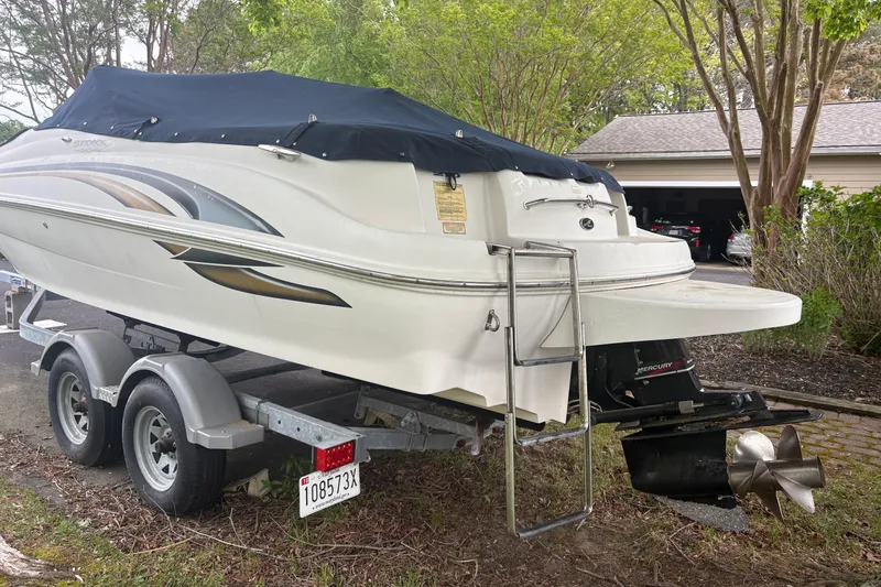 Slide: The Image of 2001 Sea Ray 210 Sundeck boat on trailer, covered, parked near garage. - 7