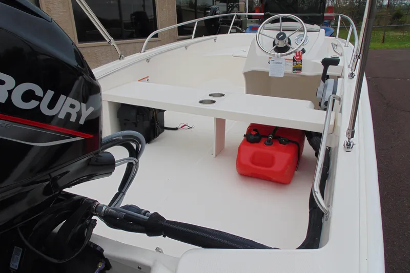 Slide: The Image of 2026 Boston Whaler 130 Super Sport boat interior with Mercury engine and red fuel tank. - 11