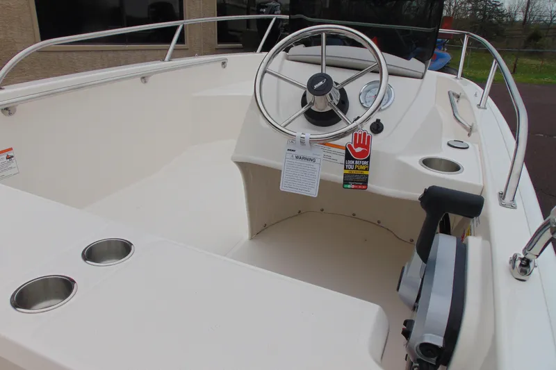 Slide: The Image of 2026 Boston Whaler 130 Super Sport boat interior with steering wheel and cup holders. - 12
