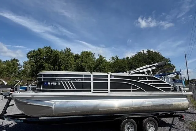 Slide: The Image of 2021 Bennington L22 pontoon boat on trailer under a clear blue sky. - 3