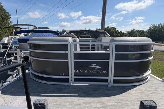Slide: The Image of 2021 Bennington L22 pontoon boat docked under a clear blue sky. - 4