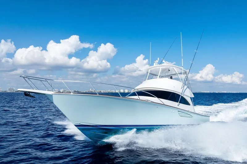 The Image of 2022 Viking 48 Convertible yacht cruising on open sea under blue sky. - 0