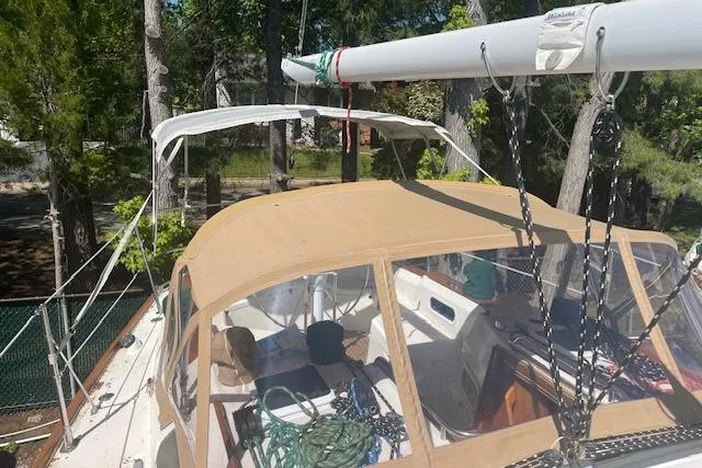 Slide: The Image of 1993 Sabre 38 sailboat with tan canopy, docked in a wooded area. - 17