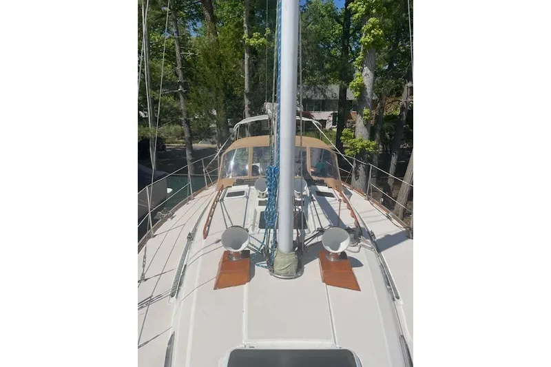Slide: The Image of 1993 Sabre 38 sailboat deck with mast and rigging, surrounded by trees. - 18