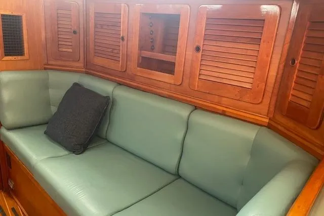 Slide: The Image of Interior of a 1993 Sabre 38 sailboat with green cushioned seating and wooden cabinetry. - 8