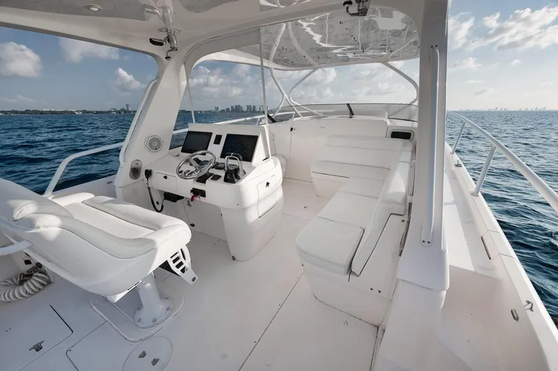 Slide: The Image of 2018 Intrepid 390 Sport Yacht interior with white seating, ocean view, and modern dashboard. - 25