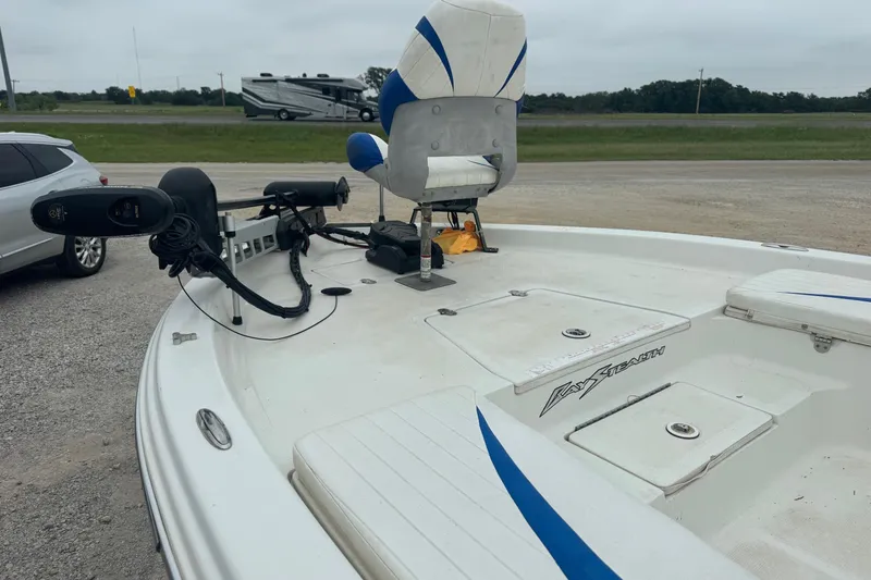 Slide: The Image of 2007 Bay Stealth 2230 boat with seating and trolling motor, parked near vehicles. - 11