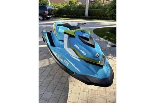 The Image of 2015 Sea Doo GTI SE 130 jet ski in blue and green on paved driveway. - 1