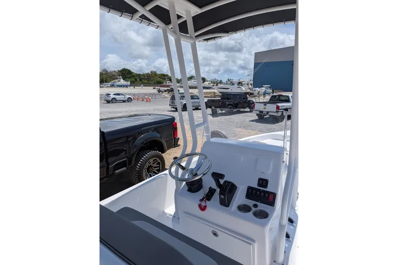 Slide: The Image of 2026 Clearwater 21 Bay boat console with steering wheel, parked vehicles in background. - 8