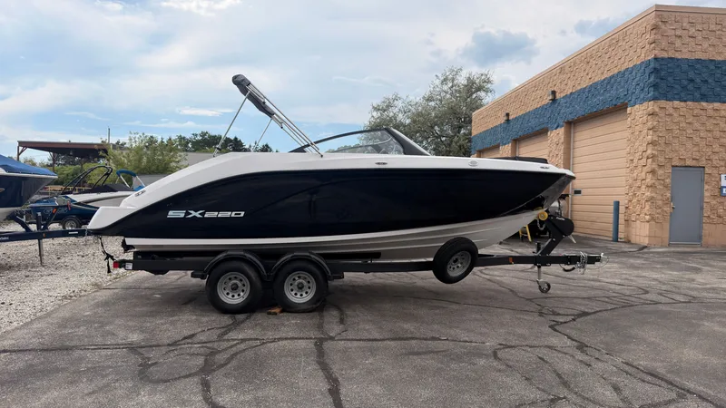 The Image of A 2026 Yamaha AR220 boat is on a trailer in a yard. - 0