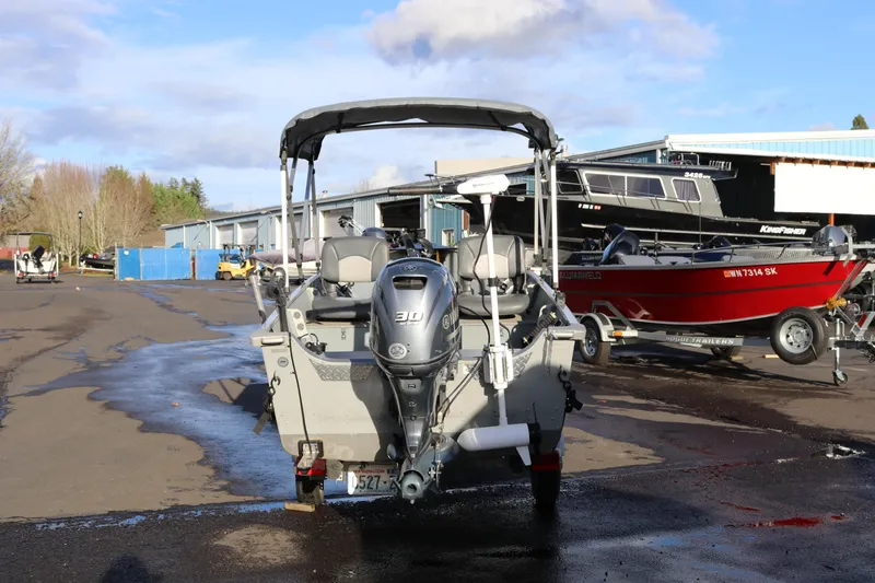 Slide: The Image of 2016 Smoker Craft Alaskan 15 boat with outboard motor in a marina setting. - 13