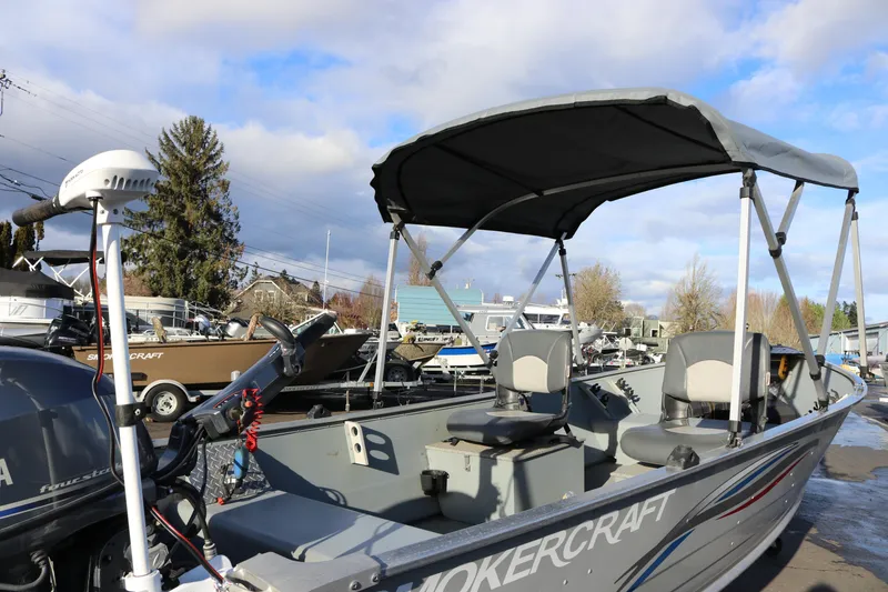 Slide: The Image of 2016 Smoker Craft Alaskan 15 boat with canopy and seating, parked outdoors. - 9