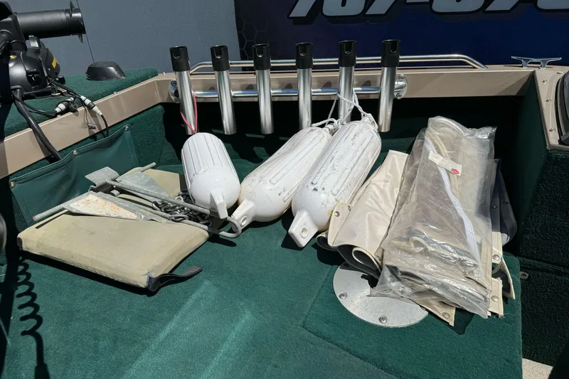Slide: The Image of Boat accessories on Lund 1600 Pro Sport, including fenders and anchor, displayed on green carpet. - 10