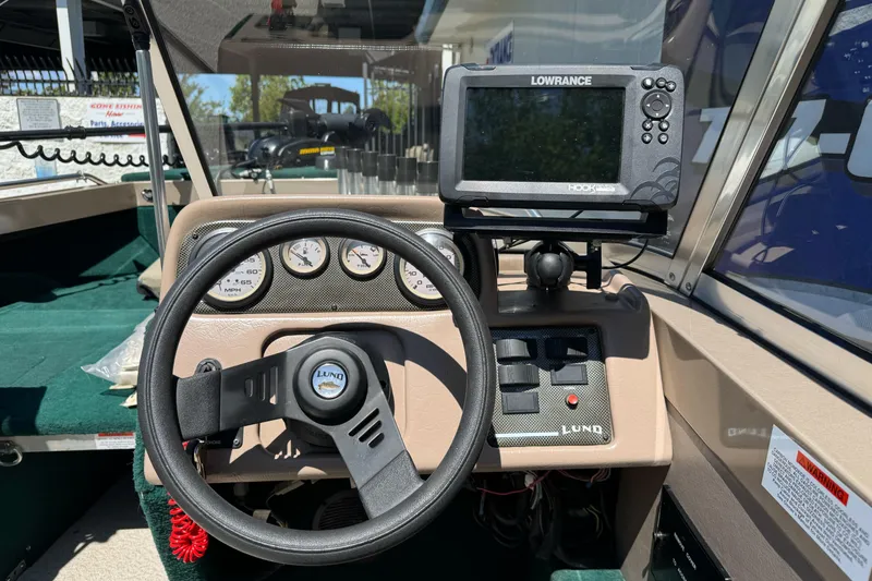 Slide: The Image of 2000 Lund 1600 Pro Sport dashboard with steering wheel and Lowrance fish finder. - 16