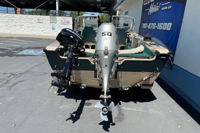 Slide: The Image of 2000 Lund 1600 Pro Sport boat with dual outboard motors in a parking lot. - 5