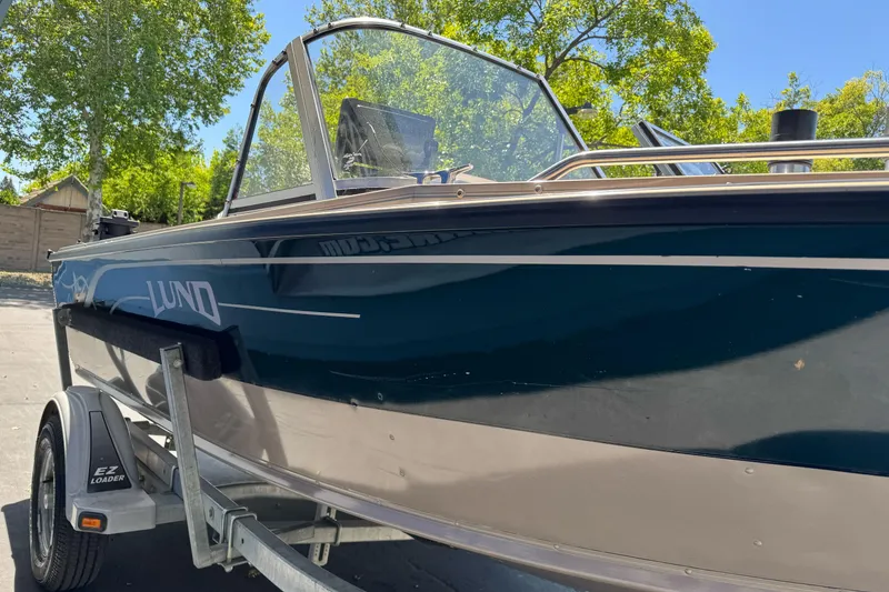 Slide: The Image of 2000 Lund 1600 Pro Sport boat on trailer, parked outdoors under clear blue sky. - 8