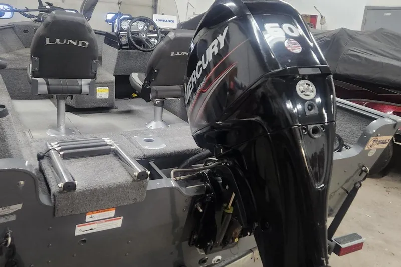 Slide: The Image of 2018 Lund 1650 Rebel XS Tiller boat with Mercury 60 HP outboard motor in a garage. - 11