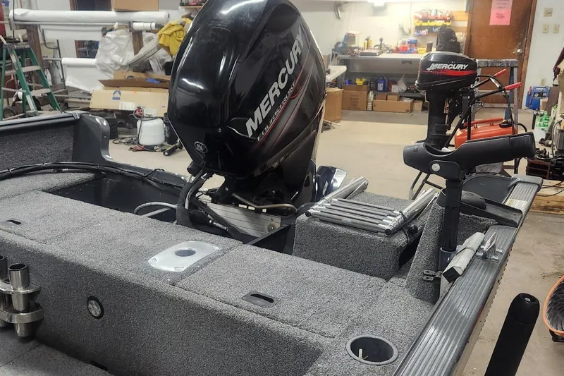 Slide: The Image of 2018 Lund 1650 Rebel XS Tiller boat with Mercury outboard motor in a workshop. - 12