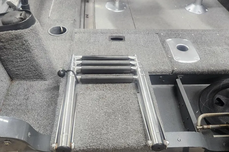 Slide: The Image of 2018 Lund 1650 Rebel XS Tiller boat interior with foldable ladder and carpeted deck. - 17