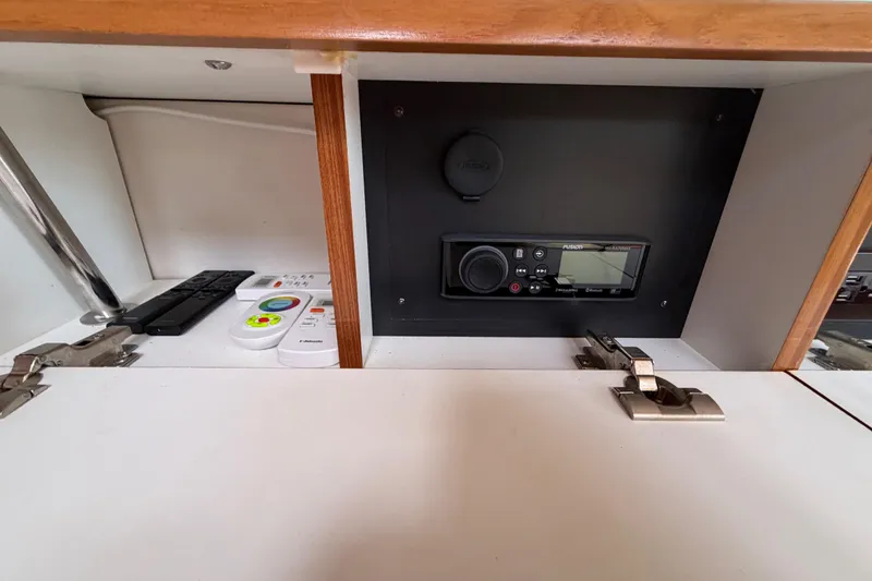 Slide: The Image of 2023 Catalina 425 interior cabinet with remote controls and Fusion stereo system. - 25