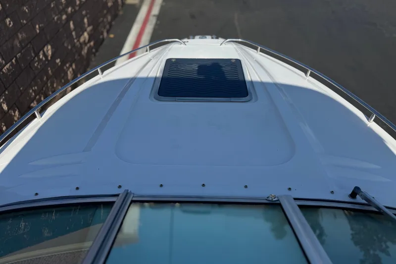 Slide: The Image of 2005 Chaparral 255 SSi boat deck with hatch, docked beside stone wall. - 11