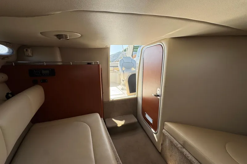Slide: The Image of Interior cabin of a 2005 Chaparral 255 SSi boat, featuring seating and a wooden door. - 29