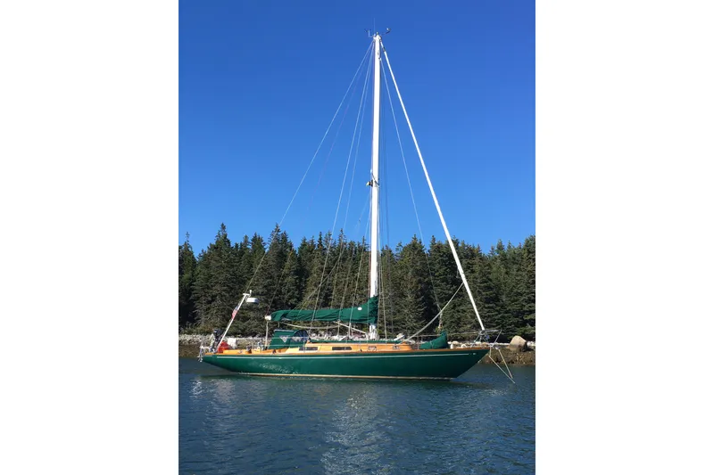 The Image of 1969 Ohlson 38 sailboat anchored on calm water with forest backdrop. - 1
