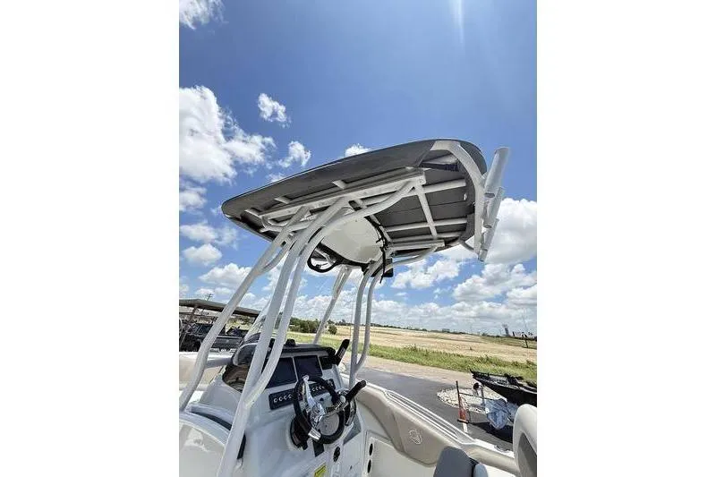 Slide: The Image of 2024 Finseeker 210 CC boat console with T-top under a clear blue sky. - 5