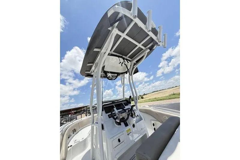 Slide: The Image of 2024 Finseeker 210 CC boat console with T-top under a clear blue sky. - 6