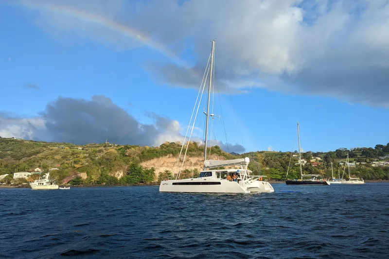 Slide: The Image of Sailboats on a scenic bay with a rainbow and lush hills in the background. - 44
