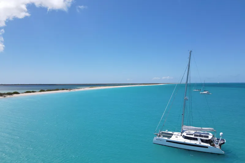 Slide: The Image of Sailboat Balance 526 on turquoise waters near a sandy beach, under a clear blue sky. - 46