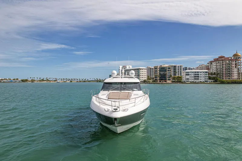 Slide: The Image of 2015 Riviera 6000 Sport Yacht on serene water with cityscape background. - 4